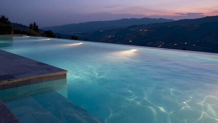 Fototapeta premium [STYLE] of a wellness retreat infinity pool at dusk showing still water merging into a valley vista with stone coping and underwater-glow textures, tranquil blue-hour with warm pool light, twilight ma