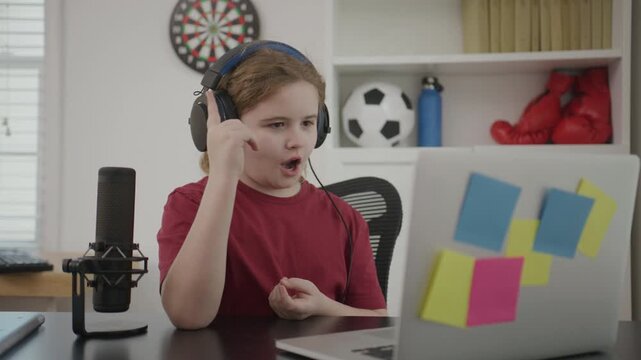 Kid records vlog at desk. Child streams video live. Kid uses microphone setup. Child creates remote content.
