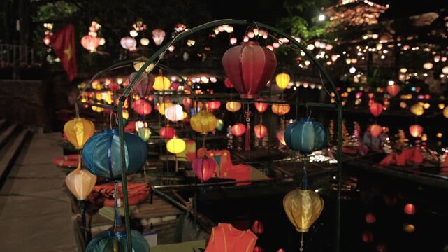 Colorful vietnamese lanterns illuminating a river with boats at night during a festival in hoi an, vietnam