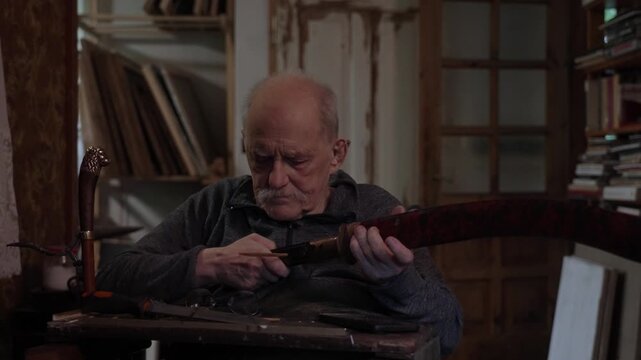 Elderly craftsman working in his old workshop, carefully restoring collectible Japanese bladed weapons