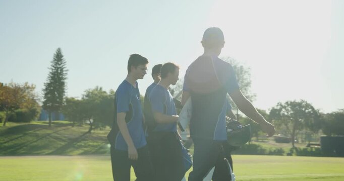 Diverse male cricket teammates striding onto sunlit field, inspecting stumps, low-angle shot