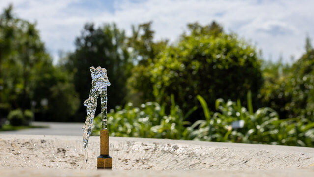 Public drinking fountain in urban green space providing access to potable water during hot weather, climate adaptation and sustainable city concept with ample copy space