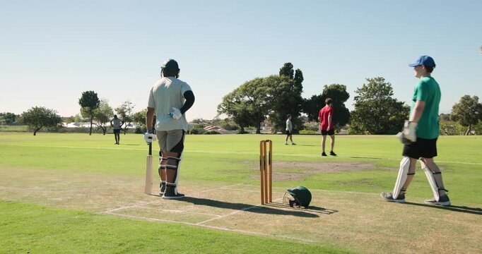 African american batsman facing bowler delivery, playing shot with cricket bat for run on field