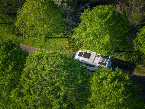 Camper van parked by canal surrounded by trees in Belgium
