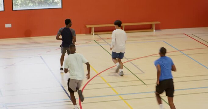 After quick pass, diverse male athletes dribbling basketball toward hoop contesting rebound