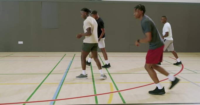 African american male team sprinting court, walking back, lunging for ball, sprinting again