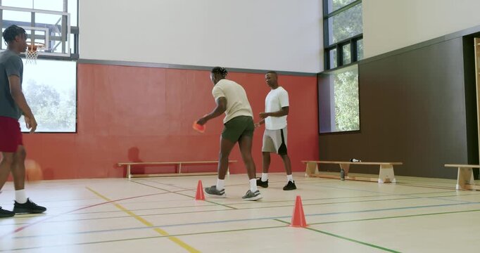 Coach blowing whistle guiding trainees dribbling ball around cones boosting coordination