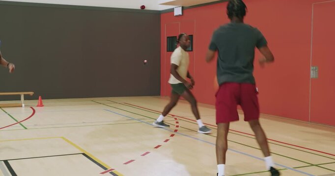 Jogging into the hardwood african american teammates training in basketball passing drill