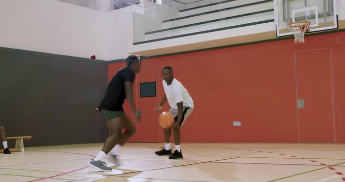 Meeting at gym court african american male friends dribbling basketball in drill, shaking hands