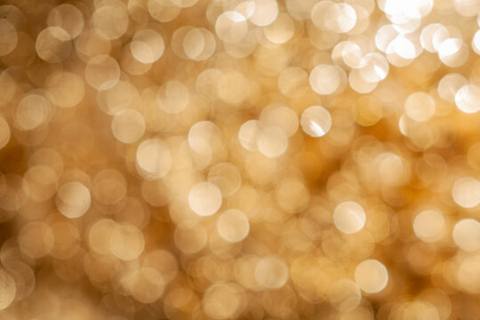 Bokeh lights shine in a warm golden hue creating an abstract background effect