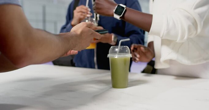Man using phone on reader at counter, diverse female friends taking drinks and chatting