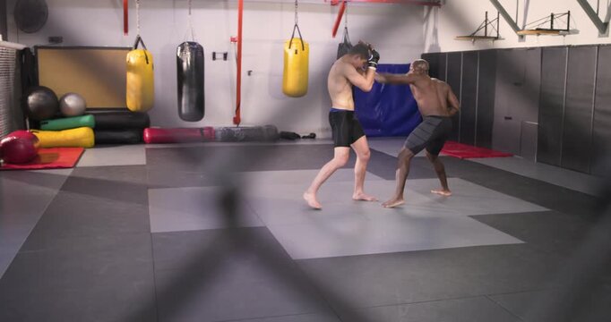 Diverse male fighters stepping in, feinting jabs, blocking and countering inside mma cage in sparr