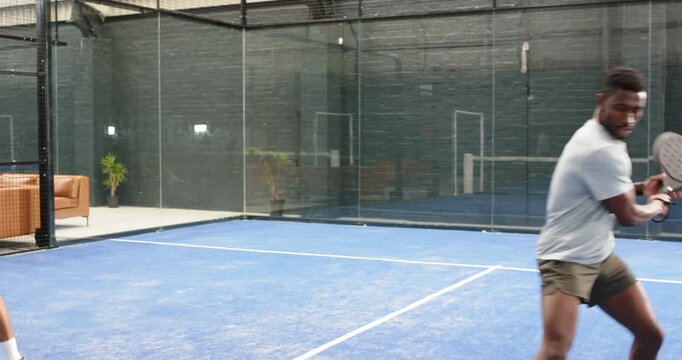 Receiving lobbed ball, diverse male friends executing volley, tracking return with paddles