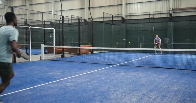 African american man responding to return, hitting paddle ball, rallying on court, copy space