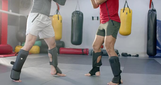 Diverse male sparring partners responding to shin check by exchanging kicks and punches