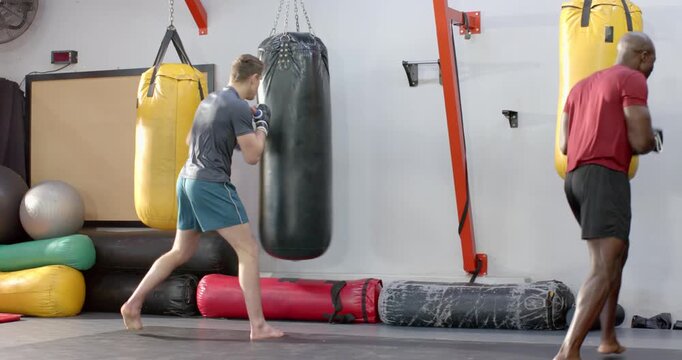 Diverse male fighters performing bag work, African American exiting as White athlete doing combos
