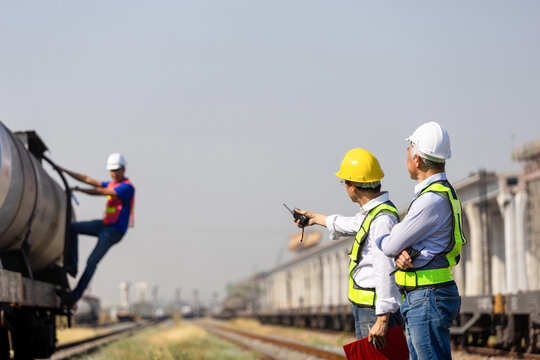 Logistics managers inspecting cargo train operations at railway freight yard, Engineer team supervising rail transport and freight operations at commercial freight terminal