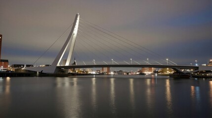 Fototapeta premium The Erasmus Bridge in Rotterdam, Netherlands, stands out at dusk with its single white pylon and multiple steel cables.