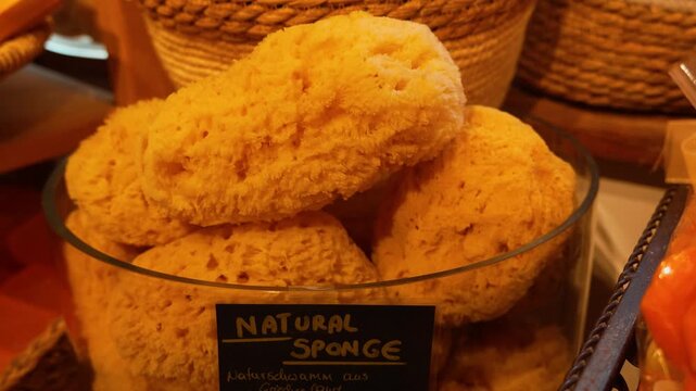 Close-up footage of a popular Austrian honey loofah sponge featuring a round shape and natural texture. The scene captures the authentic details and rustic charm of this traditional wellness 