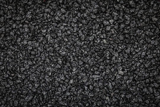 Dark gravel surface with small stones scattered across the ground shown in detail in natural light