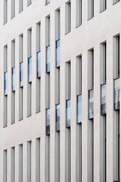 White facade shows narrow windows and vertical architecture rhythm, where minimal urban building pattern defines a clean exterior surface