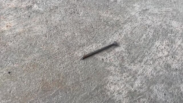 Rusty metal nail on rough concrete surface close up