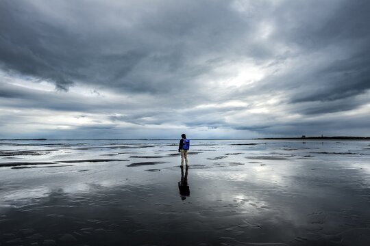 Lonely hiker on the beach, dramatic clouds, reflection, Cape Stokksnes, Hornvik Bay, Austurland, Iceland