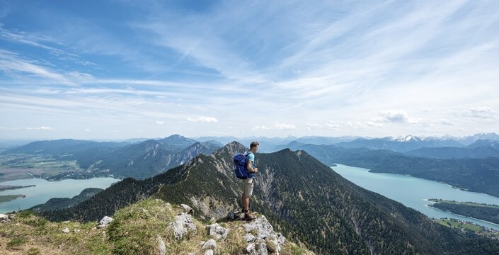 Hiker at Heimgarten, view from the top with Lake Kochel, Walchensee and Herzogstand, Upper Bavaria, Bavaria, Germany