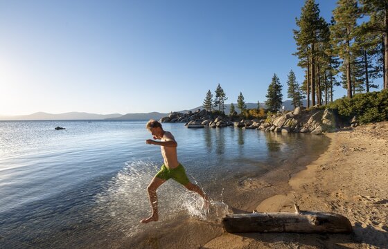 Young man running in the water on a sandy beach, Splashing water, Bay on Lake Tahoe, Sand Harbor Beach, Sand Harbor State Park, Shore, California, USA