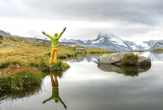 Hiker stretches his arms into the air, Lake Stellisee, Matterhorn at the back, cloudy, Wallis, Switzerland