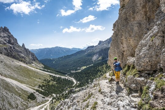 Hiker at the Rosengarten group, walk around, panoramic view into the valley towards Pera di Fassa, Dolomites, South Tyrol, Trentino-Alto Adige, Italy