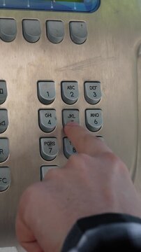 Footage of a classic vintage telephone box featuring a retro wall-mounted phone with numbered keypad buttons. A hand is seen pressing individual numbers on the dial pad