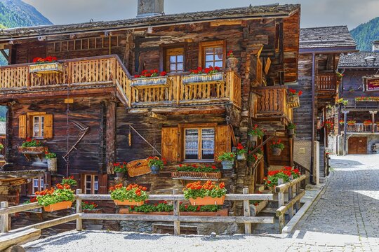 Paved footpath surrounded by old wooden houses, flower boxes on balconies and windows, historic village centre, Grimentz, Val d'Anniviers, Valais Alps, Canton Valais, Switzerland