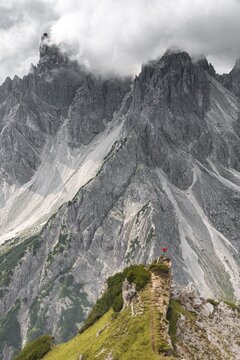 Mountaineer, woman standing on a ridge and looking into a cirque, dramatic clouds, in the back rock faces of Cimon di Croda Liscia, Auronzo di Cadore, Belluno, Italy