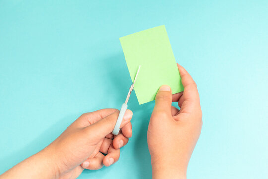Left handed man holding scissors and cutting paper with  hand, lefty concept, handycraft as left hander