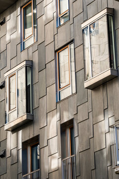 gray windows and shadow mark an Oslo apartment facade, giving a modern residential urban exterior a quiet building rhythm across panels