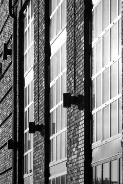 Monochrome shadow divides black and white facade planes, where brick and windows give urban architecture a stark building exterior rhythm