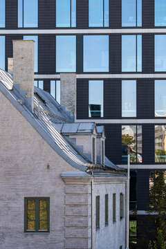 Modern glass windows rise behind a historic building facade, creating urban architecture contrast across a layered exterior city block