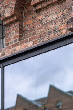 A reflective window sits beneath a brick facade, carrying urban architecture detail, building texture and exterior depth across glass