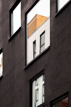 Narrow windows cut through a dark facade, where urban architecture turns a building exterior into vertical contrast and detailed depth