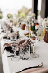 Fototapeta premium A refined banquet table prepared for a formal occasion featuring crystal glassware, neatly folded napkins, and polished cutlery. Soft light enhances the upscale dining setup for guests 