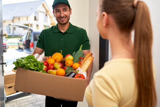 Smiling deliveryman giving grocery order to customer at doorway