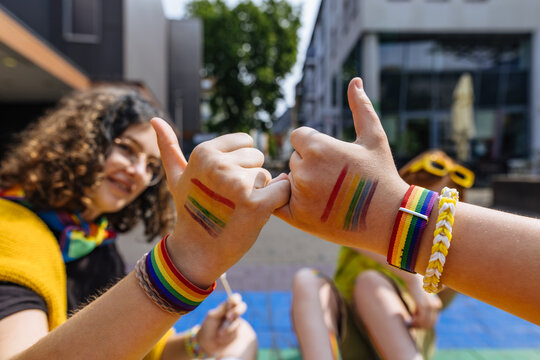 Friends making pinky promise at outdoor pride parade