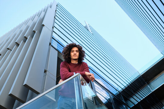 Caucasian young man leaning on railing while modern office building in background