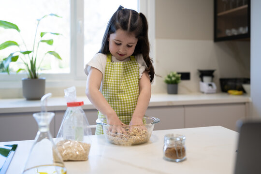 Baker kneading dough mixture in bowl on kitchen counter