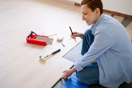 Woman installing wood laminate flooring during diy project