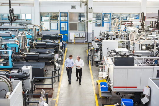 Two men with tablet talking in factory shop floor