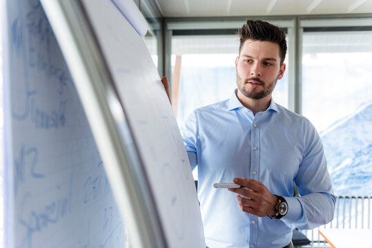 Businessmen standing at flipchart in office