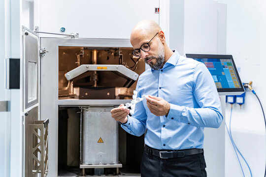 Man holding workpiece at 3d printer