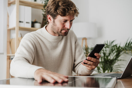 Businessman using smart phone by solar panel and laptop at workplace